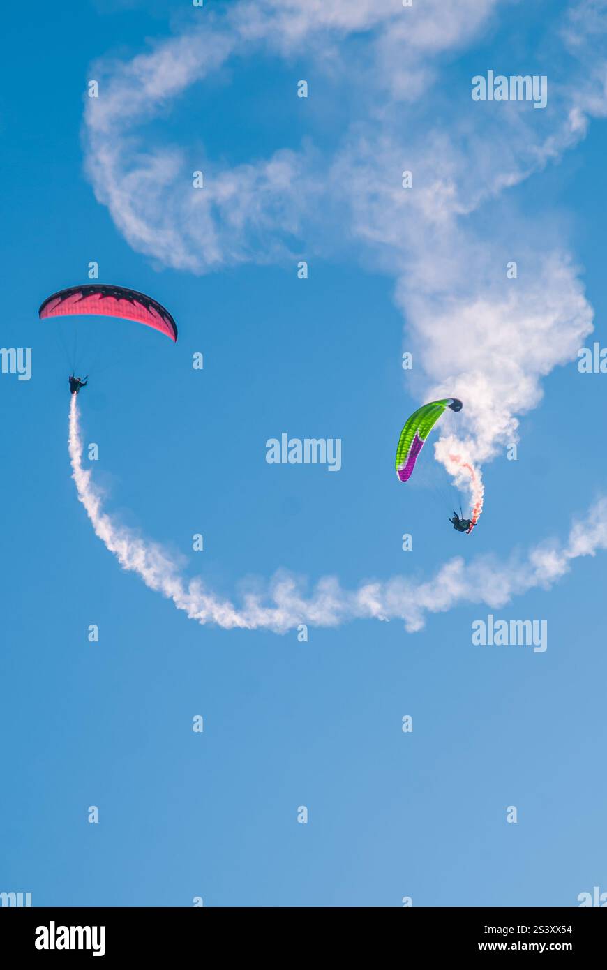 spectacle aérien palpitant avec deux parapentes effectuant des manœuvres acrobatiques. Banque D'Images