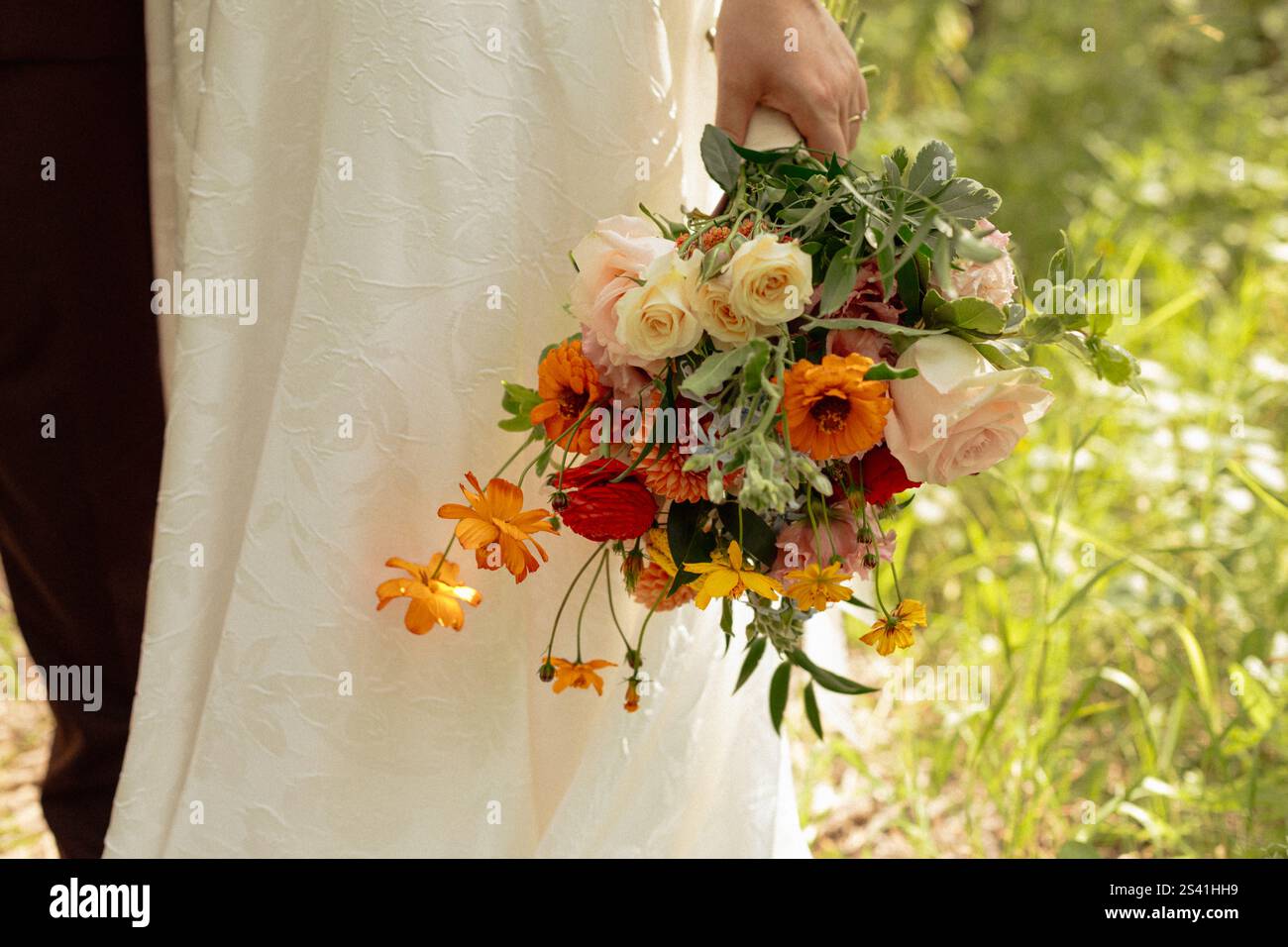 Mariée tenant le bouquet de mariage d'été dans la lumière du soleil Banque D'Images