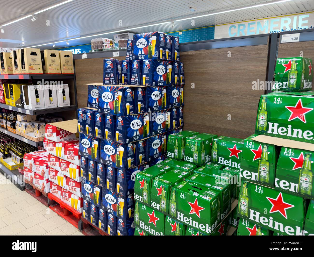 Piles de canettes de bière et de boîtes dans une allée de supermarché avec une sélection vibrante de marques dans un magasin de détail très fréquenté Banque D'Images