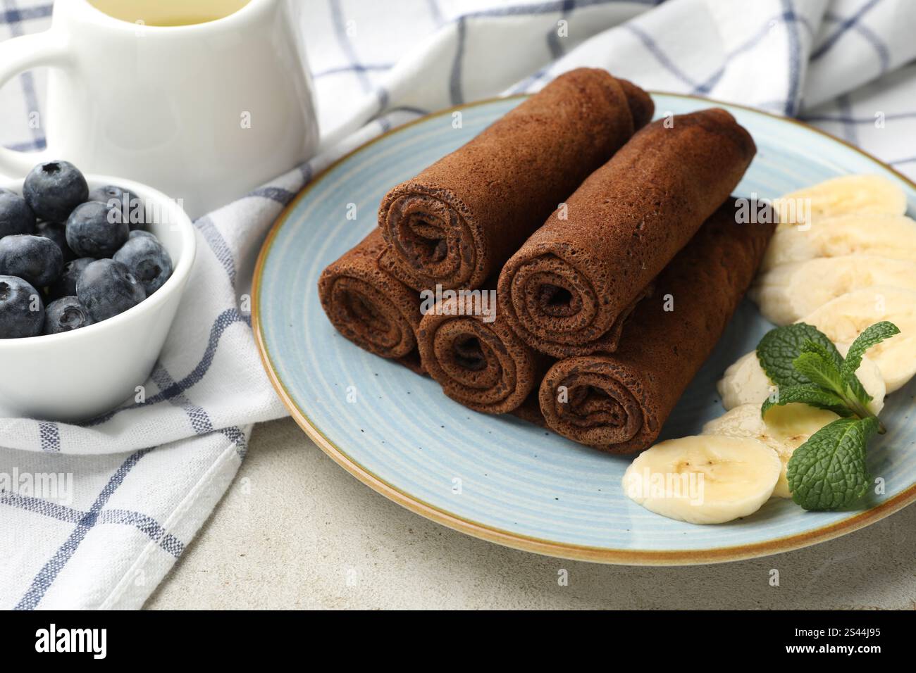 Délicieuses crêpes au chocolat à la banane et aux myrtilles servies sur une table lumineuse, en gros plan Banque D'Images