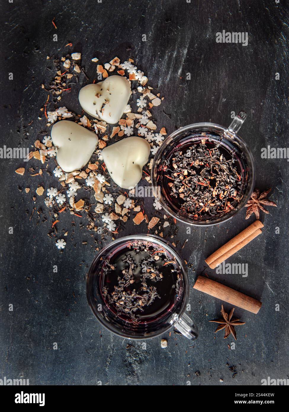 vue de dessus sur le vin chaud dans deux verres avec des biscuits en forme de coeur et des épices disposés sur un fond d'ardoise grise Banque D'Images