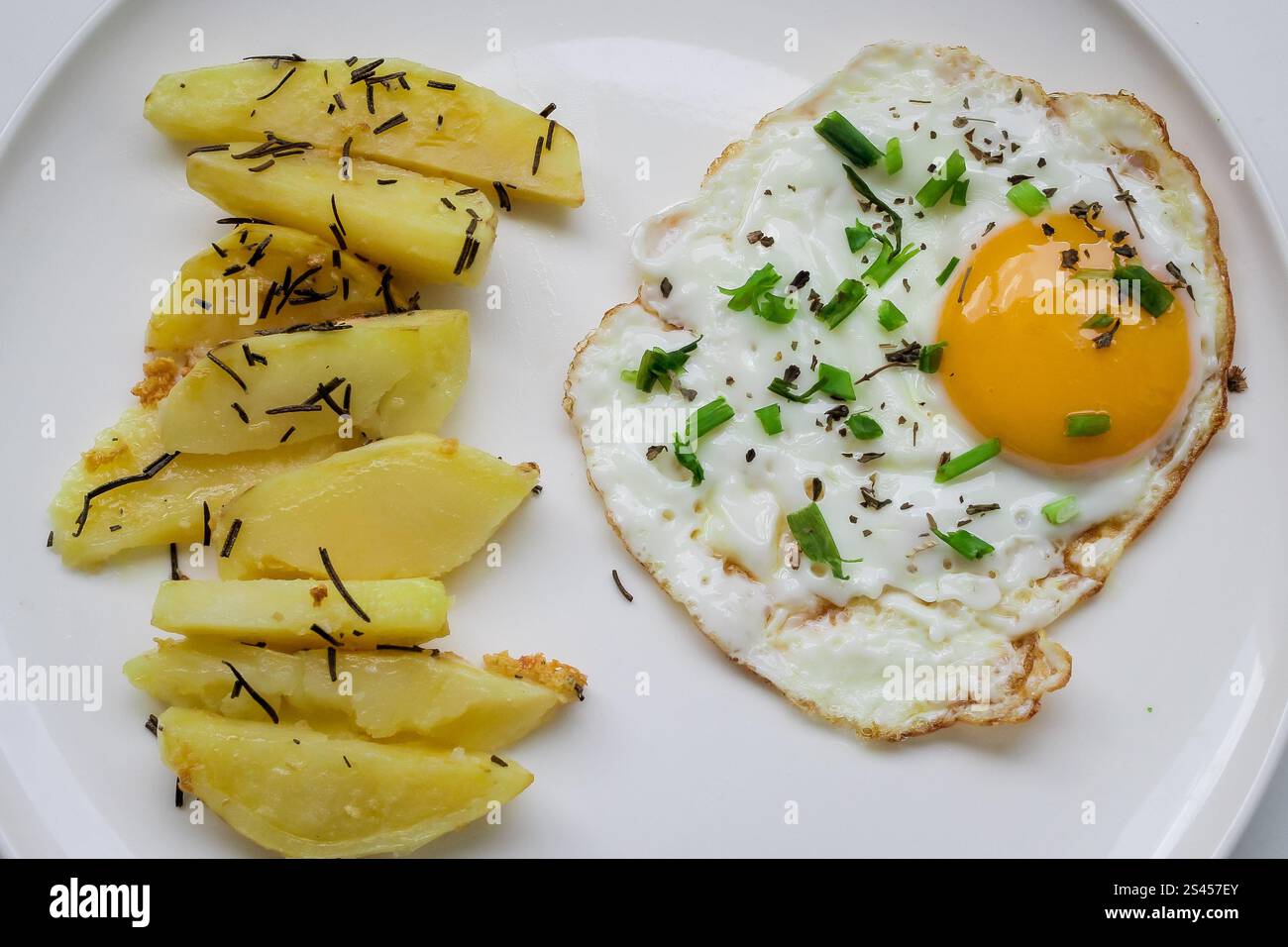 oeuf frit avec pain grillé décoré de petits pois verts sur assiette blanche. avec pomme de terre pour le petit déjeuner Banque D'Images