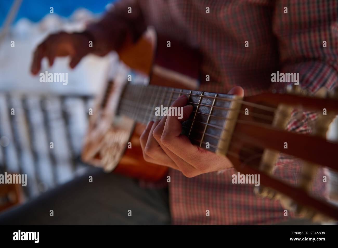 Une image en gros plan montrant des mains jouant de la guitare classique dans un cadre extérieur détendu. La scène transmet un sentiment de créativité, de compétence et de passion Banque D'Images