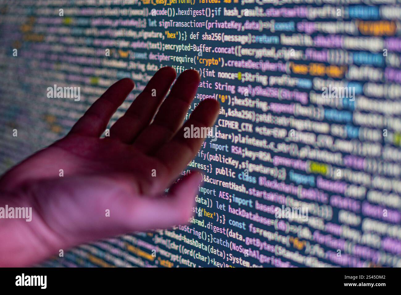 L'image montre une personne interagissant avec un grand écran de programmation à code couleur, éventuellement Python, en utilisant des gestes de la main tout en se concentrant sur la manipulation du code Banque D'Images