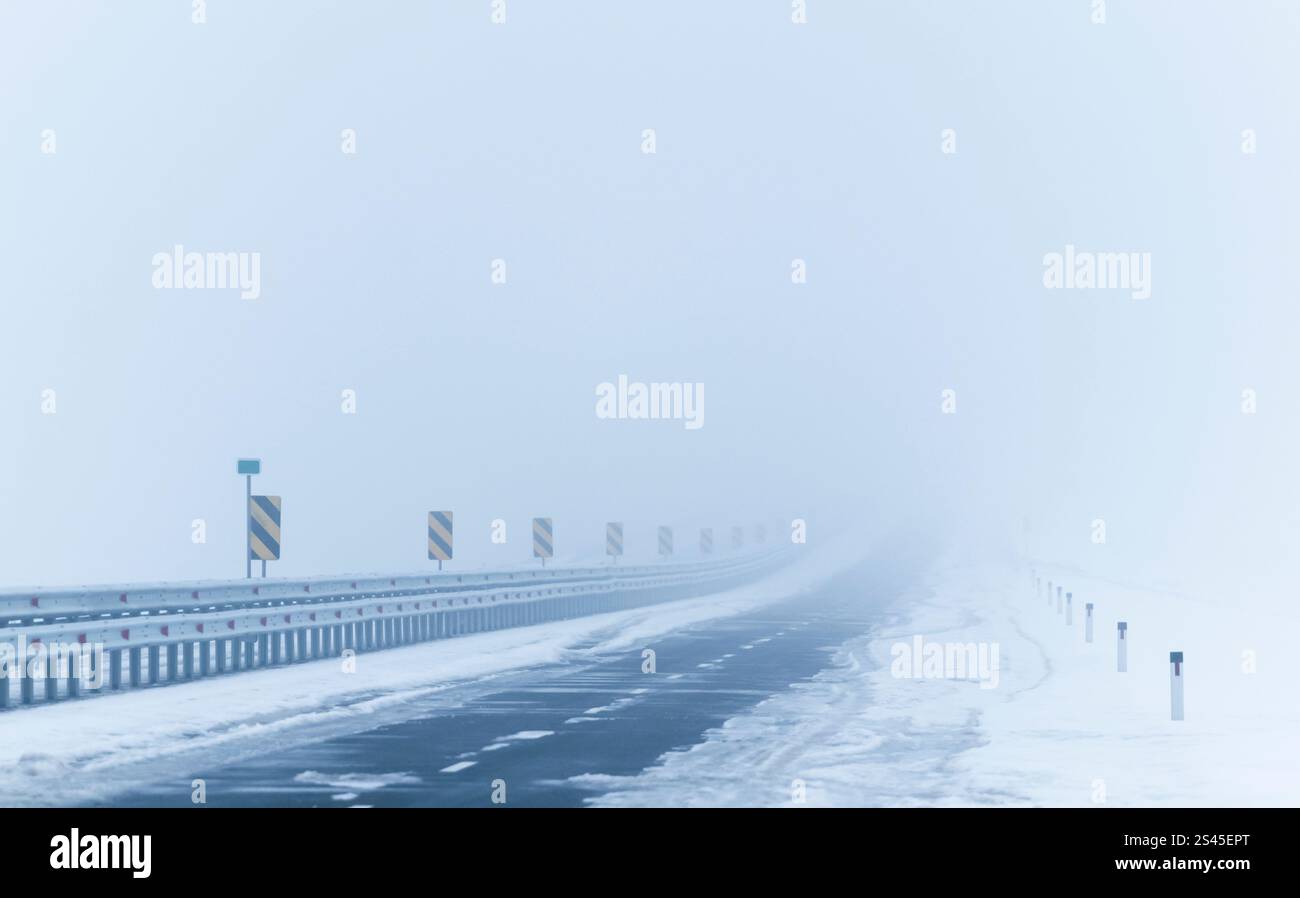 Route enneigée en cas de brouillard épais. Météo hivernale Banque D'Images