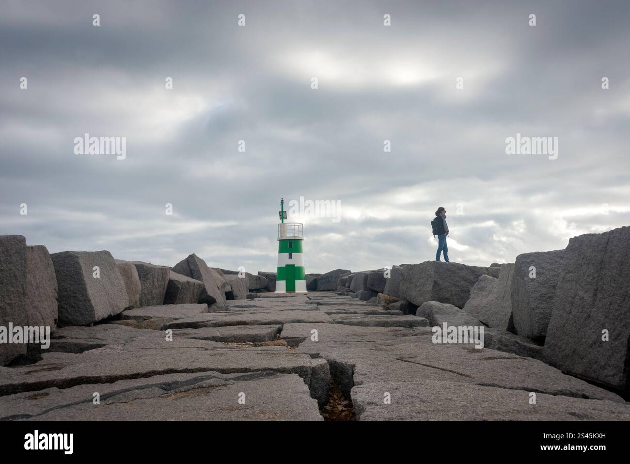 femme debout sur les rochers près d'un phare sur une chaussée Banque D'Images femme debout sur les rochers près d'un phare sur une chaussée Banque D'Images