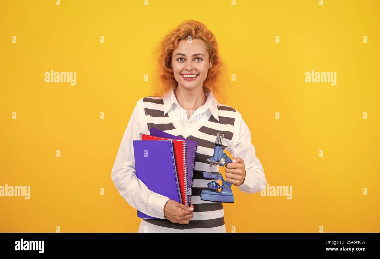 Professeur avec microscope sur jaune. Sciences biologiques pour la femme. La recherche microscopique. Une femme professeur de biologie scolaire tient un microscope. Femme enseignante de biol Banque D'Images