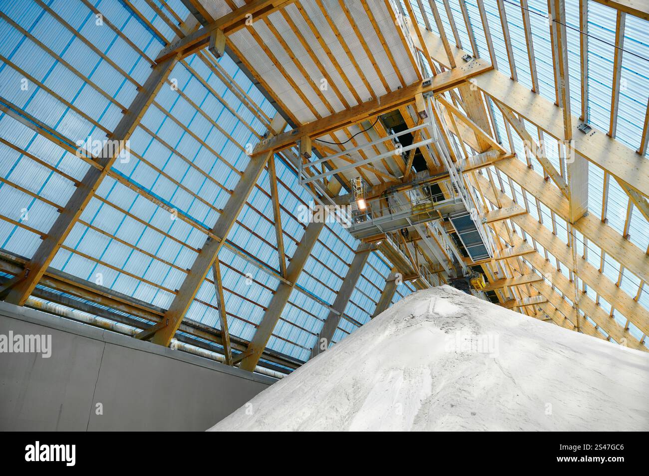 Vue intérieure d'un entrepôt d'usine chimique présentant une grande pile de matériaux sous un système de convoyeur et une structure de toit en verre Banque D'Images