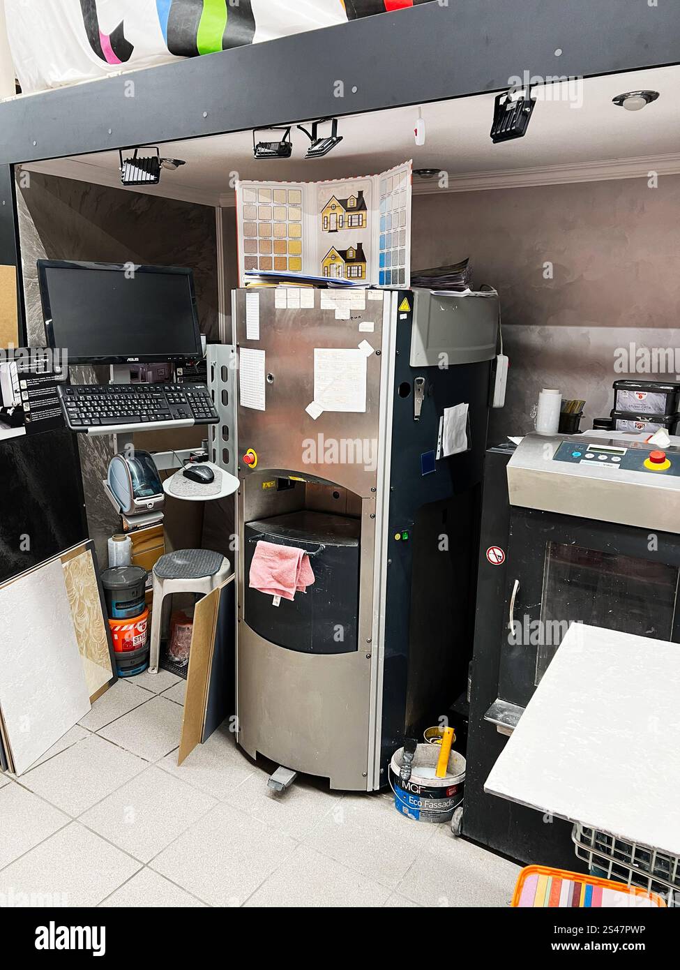 Kiev, Ukraine - 10 janvier 2025 : un espace de travail professionnel avec une machine de mélange de peinture, un affichage de nuancier, et divers outils, véhiculant une atmosphère Banque D'Images