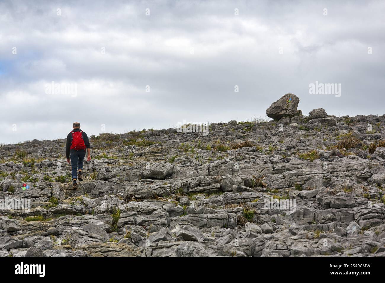 Randonneur marche sur des dalles de calcaire de forme bizarre, collines dans le paysage karstique, parc national de Burren, comté de Clare, Irlande, Europe Banque D'Images