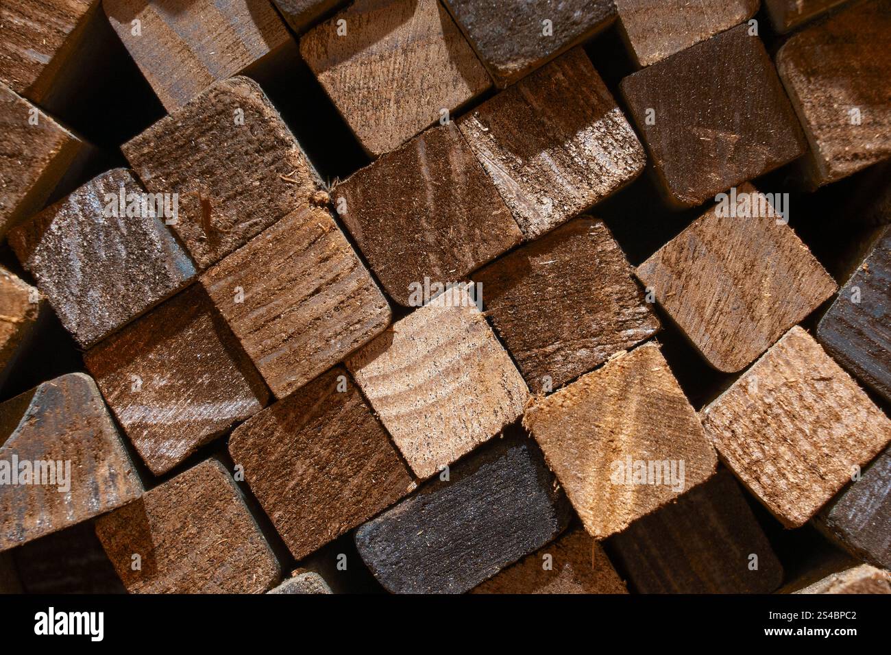 Vue rapprochée de blocs de bois soigneusement disposés utilisés dans la production de produits en bois, mettant en évidence les textures et les couleurs naturelles. Banque D'Images