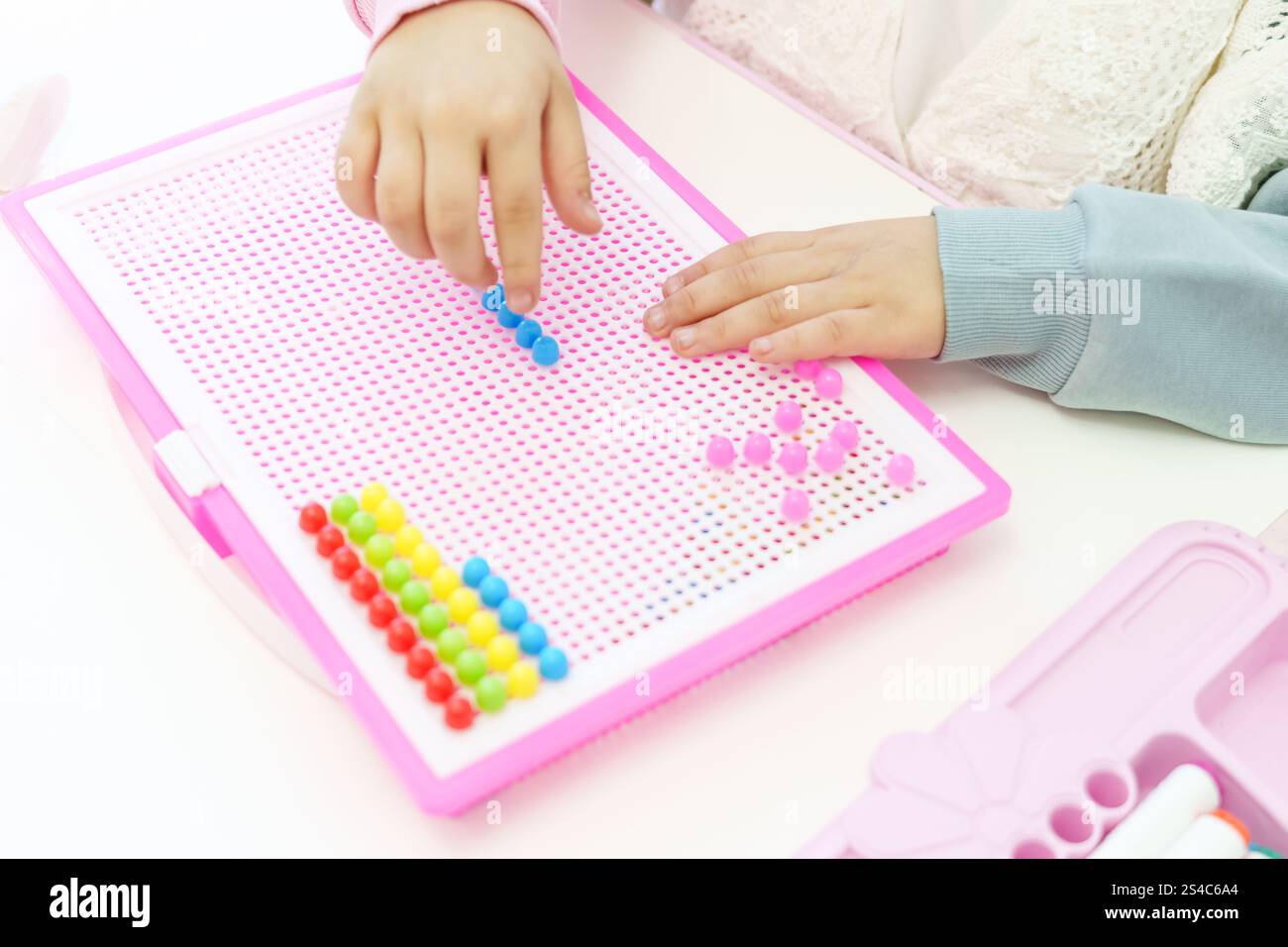 Mise au point sélective. Enfant jouant à la mosaïque de panneaux perforés. Le développement précoce de l'enfant. Motricité fine. Apprentissage et créativité. Photo de haute qualité Banque D'Images