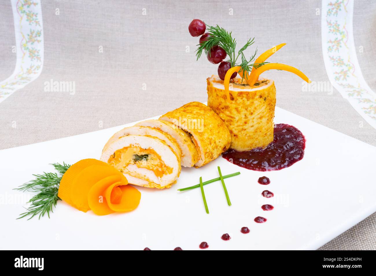 Une roulade de poulet gastronomique magnifiquement plaquée servie avec des garnitures de légumes colorées et des sauces savoureuses. Le plat met en valeur la créativité culinaire et Banque D'Images