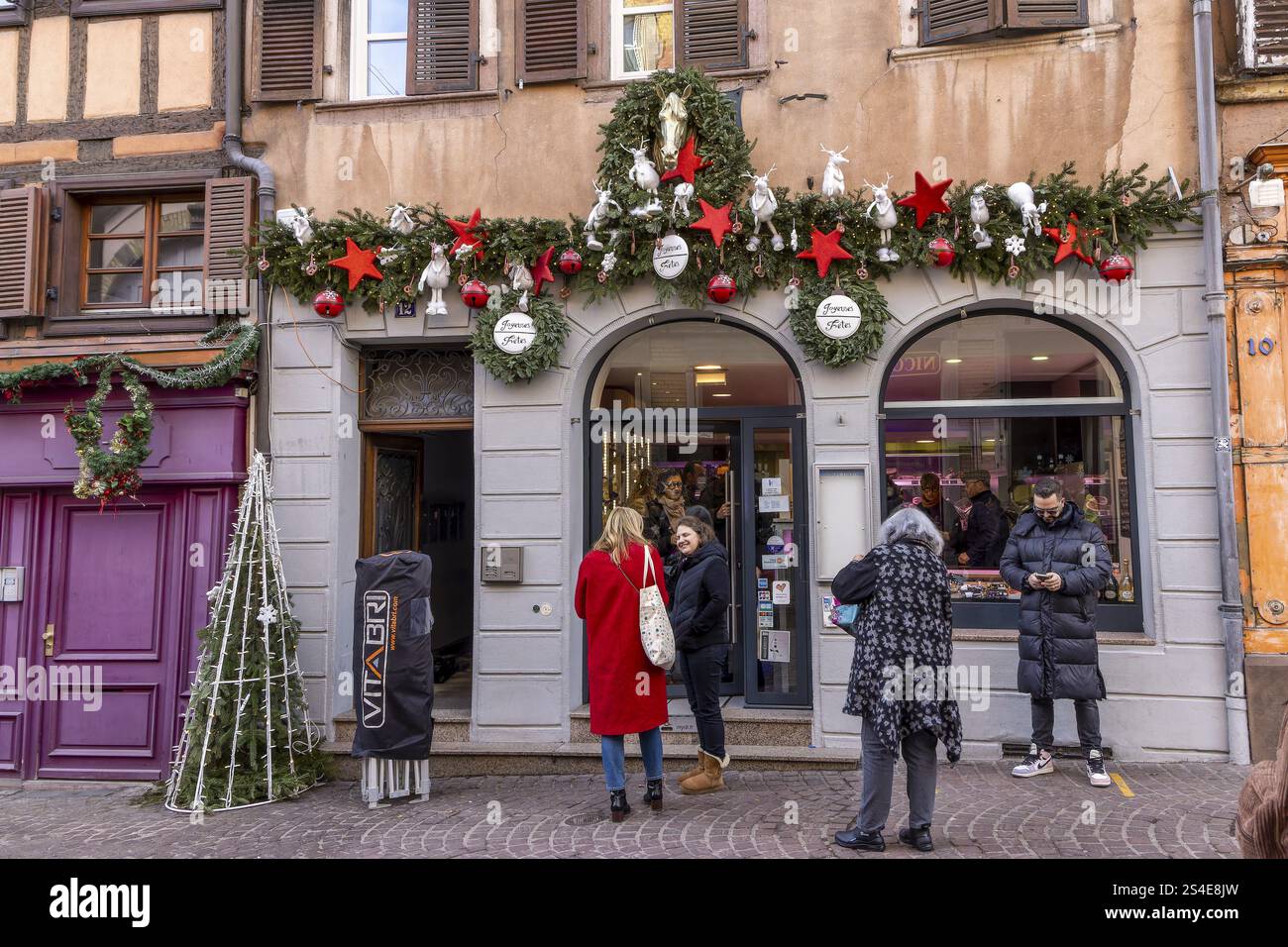Façade décorée de Noël d'une boutique avec étoiles rouges et cerfs blancs et gens marchant dans la rue, Colmar, Alsace, Département Bas-Rhin, France, UE Banque D'Images