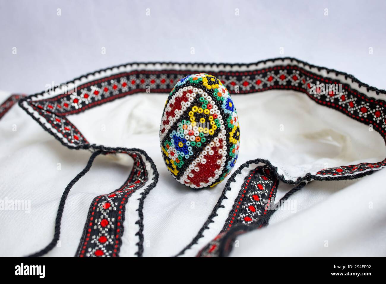 Oeuf de pâques perlé à la main. Perle, sur une blouse ou une chemise ethnique roumaine, doux focus détail gros plan Banque D'Images