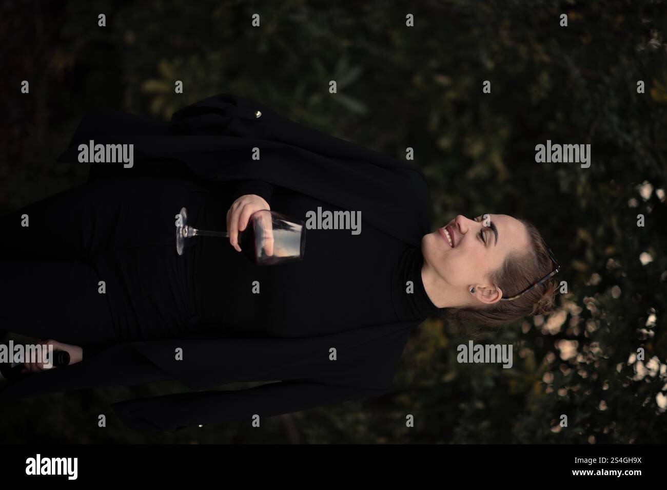 Fille avec un verre de vigne sur une partie sur la cour arrière en costume noir Banque D'Images