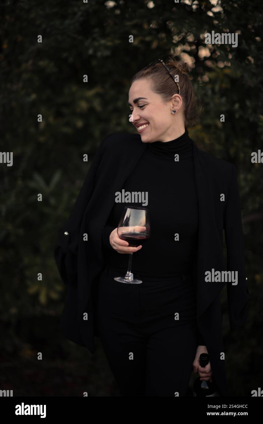 Fille avec un verre de vigne sur une partie sur la cour arrière en costume noir Banque D'Images