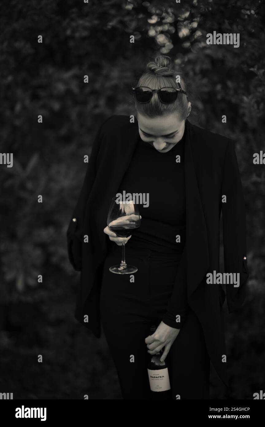 Fille avec un verre de vigne sur une partie sur la cour arrière en costume noir Banque D'Images