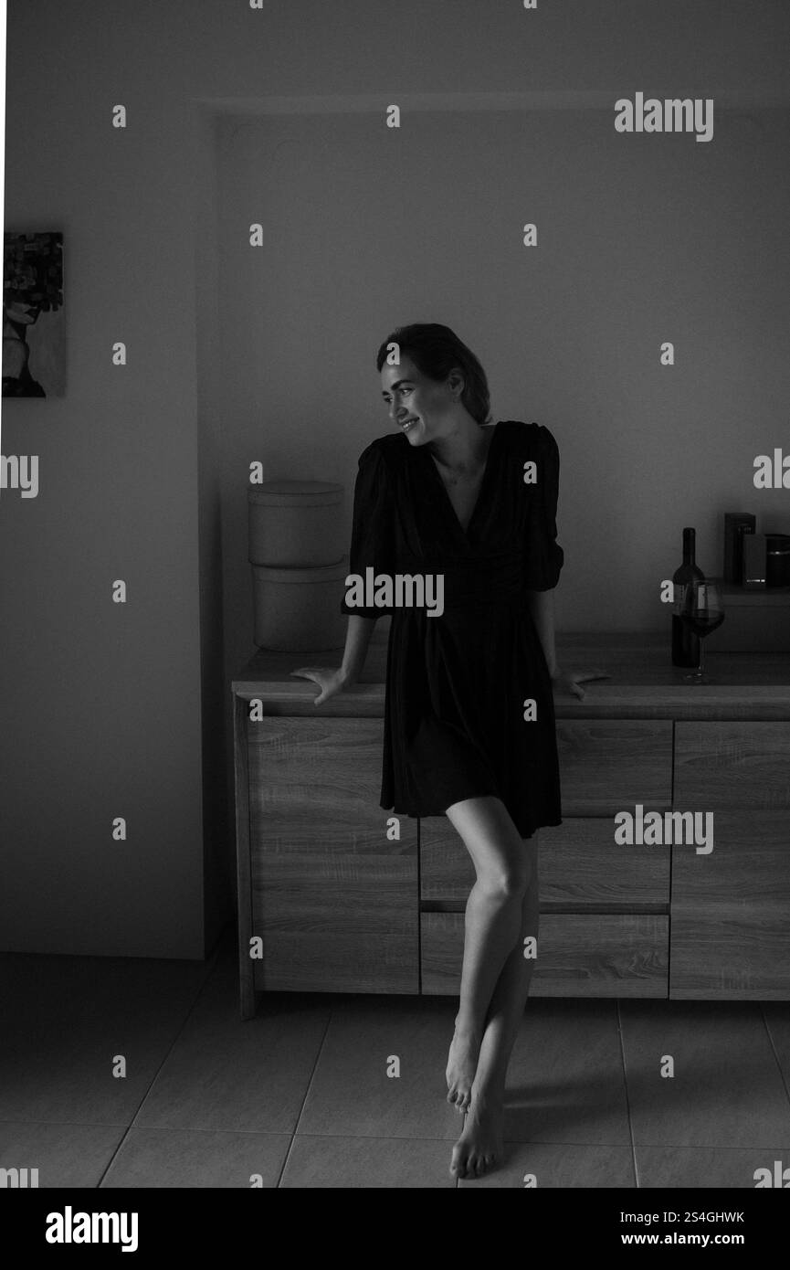 femme en robe noire est relaxant à la maison dans une atmosphère chaleureuse avec un verre de vin rouge et chat Banque D'Images