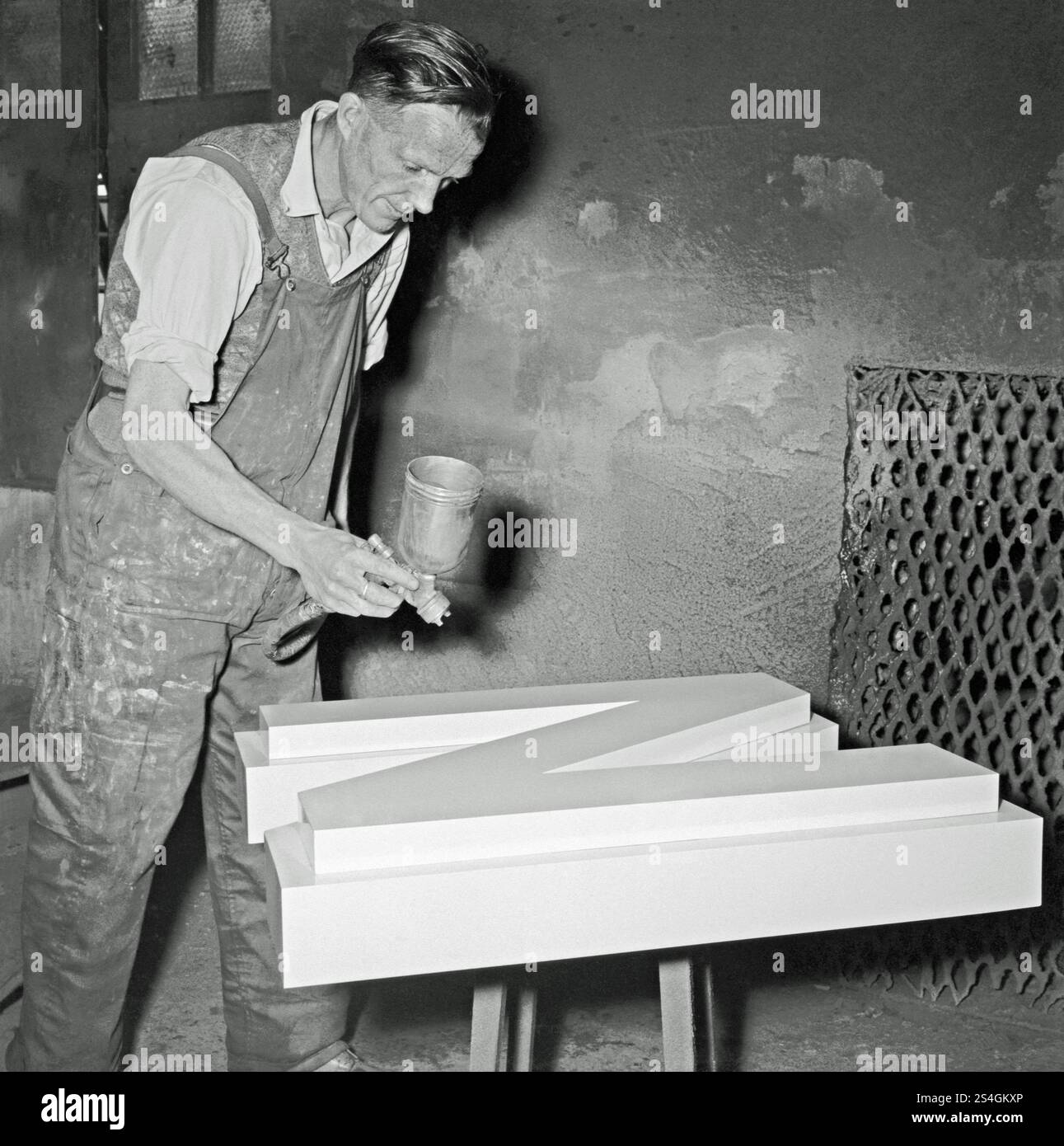 Un ouvrier peignant au pistolet une grande lettre en métal «N» dans un atelier de fonderie britannique vers 1930. Banque D'Images Un ouvrier peignant au pistolet une grande lettre en métal «N» dans un atelier de fonderie britannique vers 1930. Banque D'Images