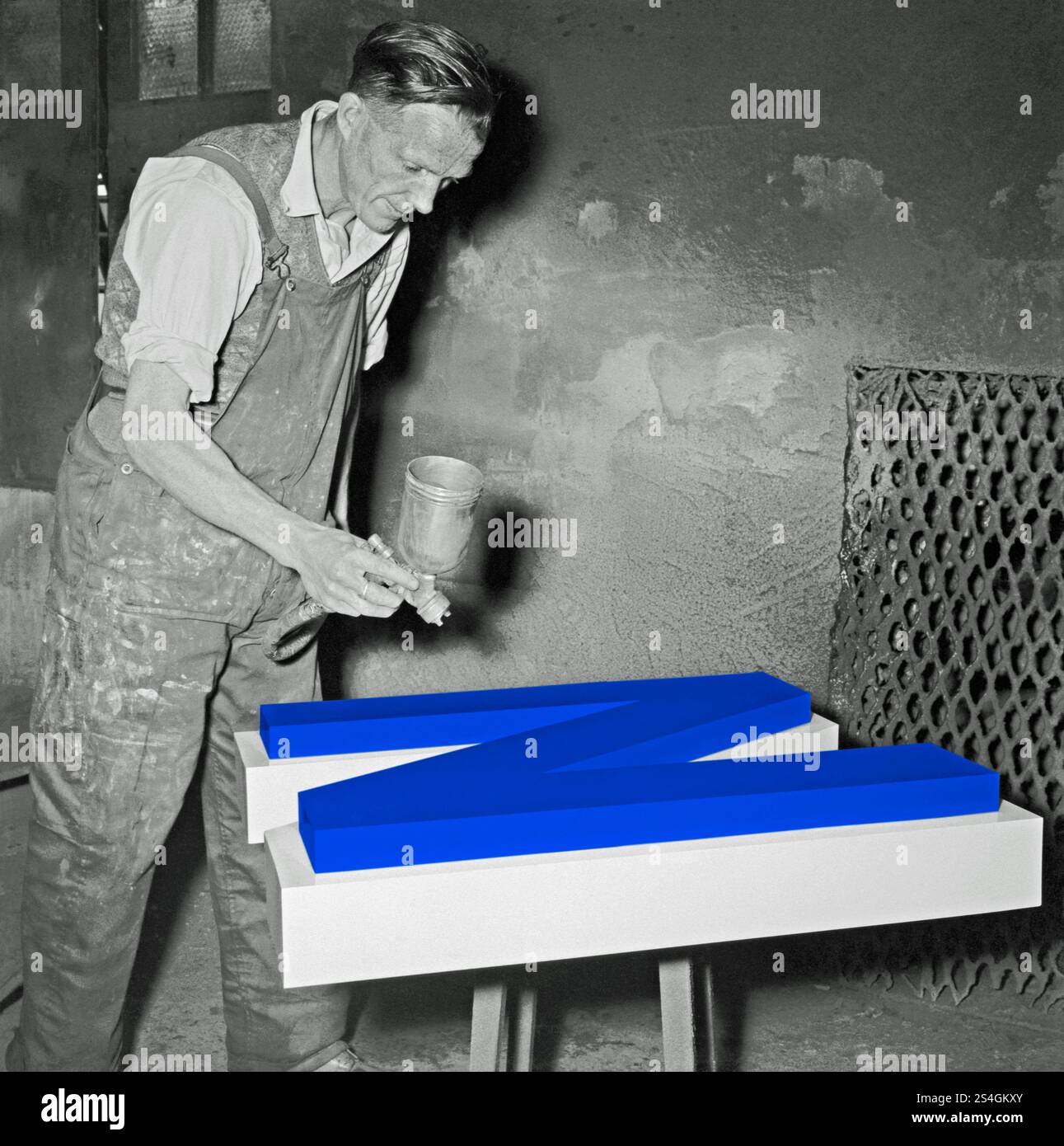 Un ouvrier peignant au pistolet une grande lettre en métal «N» dans un atelier de fonderie britannique vers 1930. Cette photographie vintage en noir et blanc a été améliorée numériquement pour que la lettre soit de couleur bleue. Banque D'Images Un ouvrier peignant au pistolet une grande lettre en métal «N» dans un atelier de fonderie britannique vers 1930. Cette photographie vintage en noir et blanc a été améliorée numériquement pour que la lettre soit de couleur bleue. Banque D'Images
