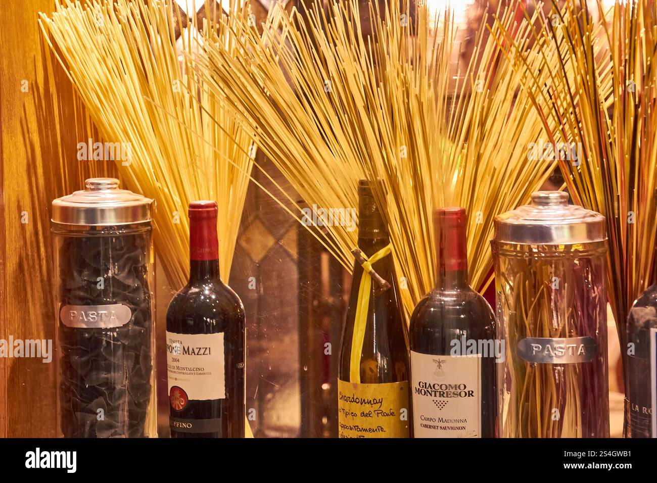 Disposition de bouteilles de vin et de pâtes dans une vitrine rustique de restaurant à Venise. Banque D'Images