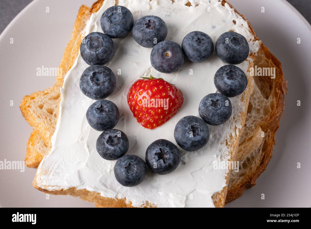 Toast garni de fromage à la crème et de fruits disposés en forme de coeur sur une assiette Banque D'Images