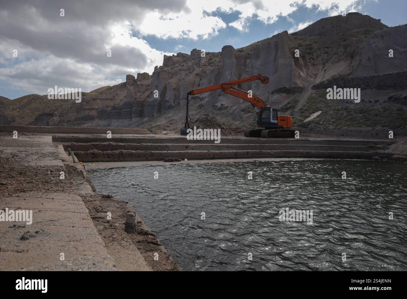 Une seule pelle orange se dresse au milieu de falaises accidentées près d'un plan d'eau calme. terrain rocheux et couches de formations de pierre Banque D'Images