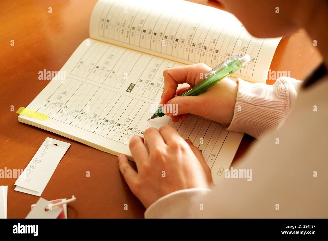 Gros plan des mains d'une jeune femme étrangère alors qu'elle écrit des kanji pour apprendre le japonais Banque D'Images