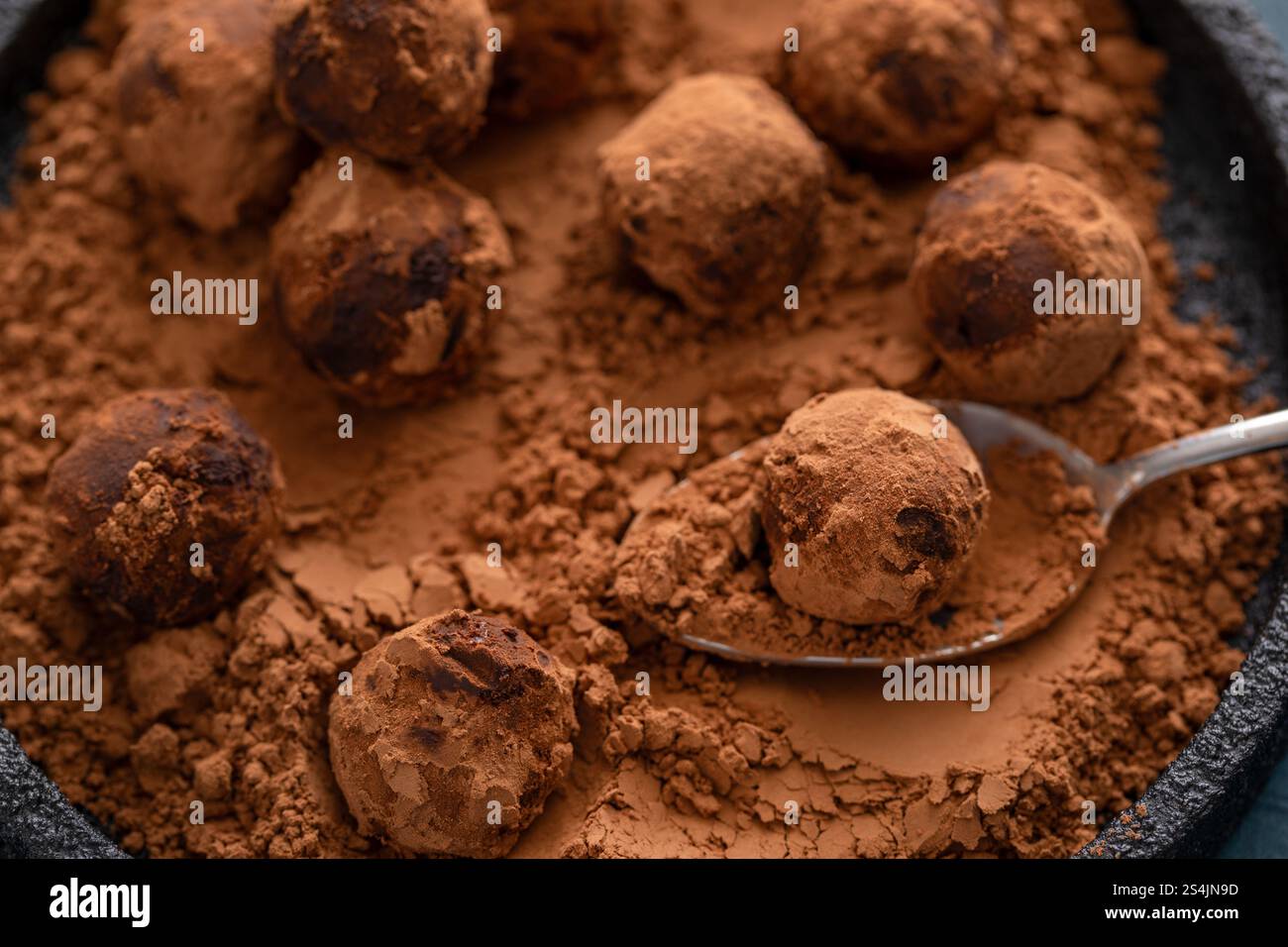 Truffes au chocolat artisanales maison saupoudrées de poudre de cacao sur une assiette avec une cuillère Banque D'Images