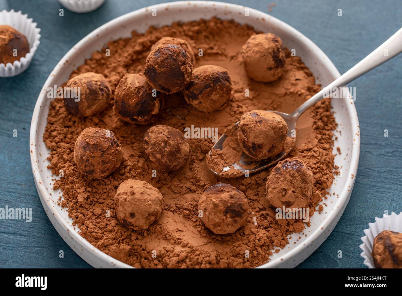 Truffes au chocolat artisanales maison saupoudrées de poudre de cacao sur une assiette avec une cuillère Banque D'Images