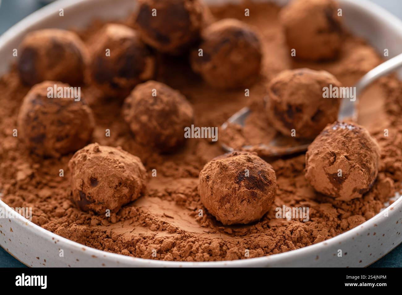 Truffes au chocolat artisanales maison saupoudrées de poudre de cacao sur une assiette avec une cuillère Banque D'Images
