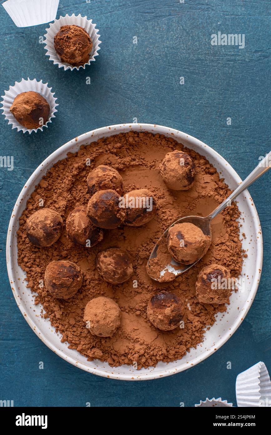 Truffes au chocolat artisanales maison saupoudrées de poudre de cacao sur une assiette avec une cuillère Banque D'Images