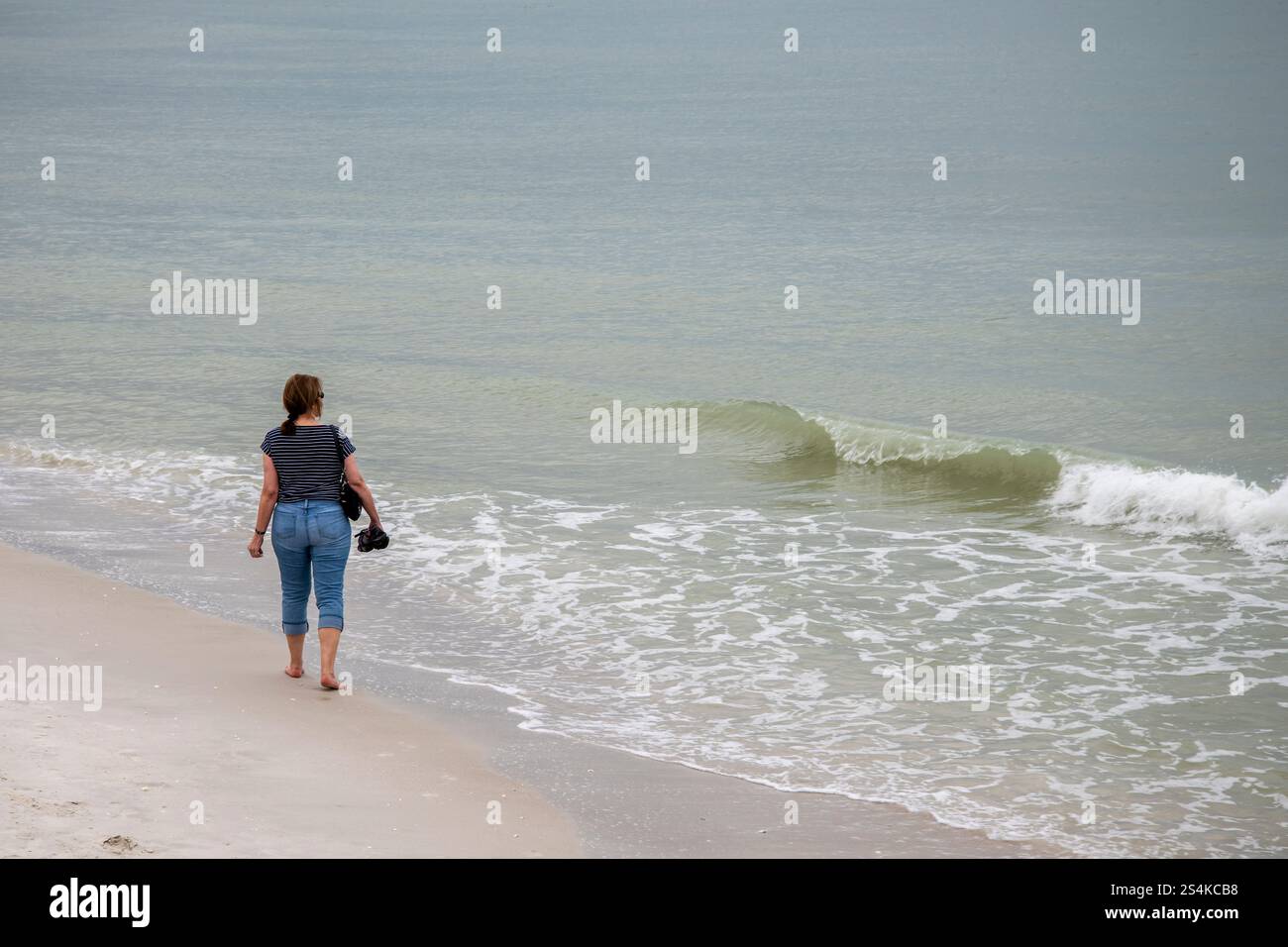 Naples, Floride. Femme marchant seule sur la plage municipale de Naples. Sur le golfe du Mexique. Banque D'Images