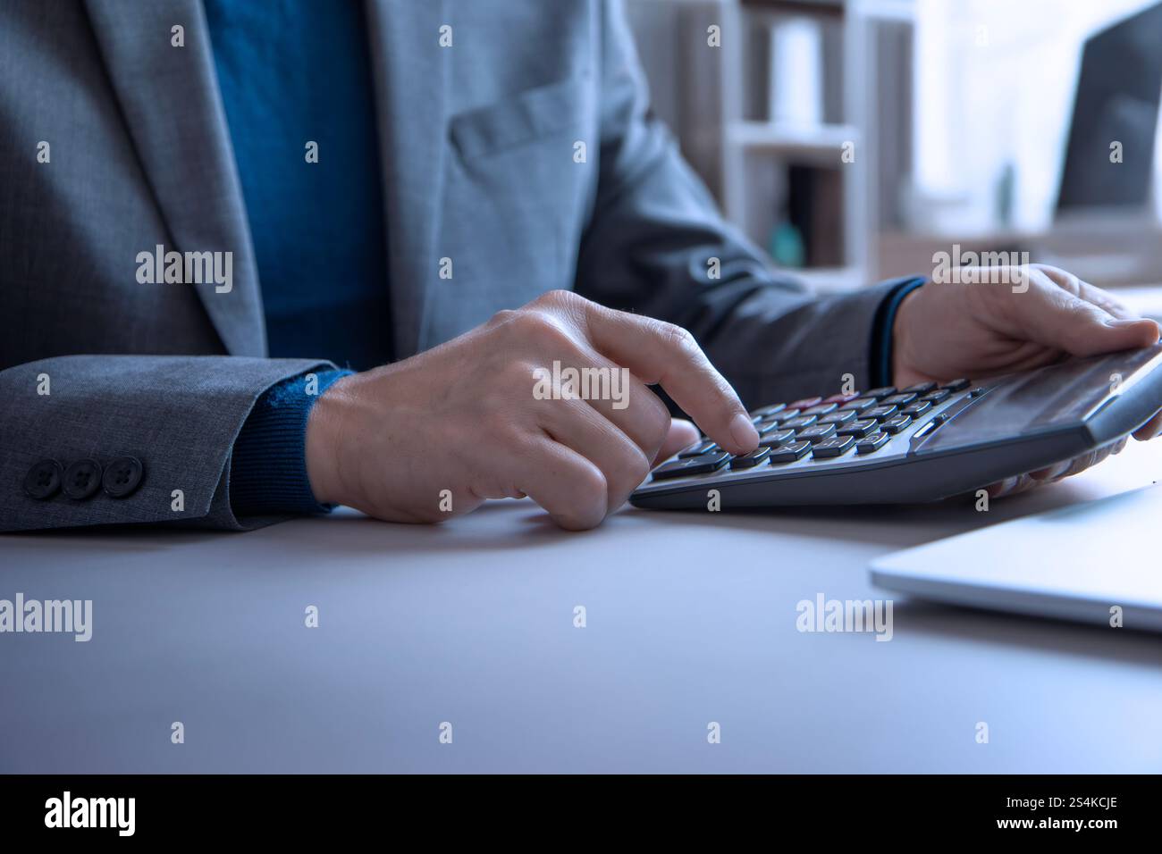 Homme d'affaires dans le bureau utilisant une calculatrice et un ordinateur portable pour examiner un retour sur investissement, budget, revenu, et planification de profit Banque D'Images