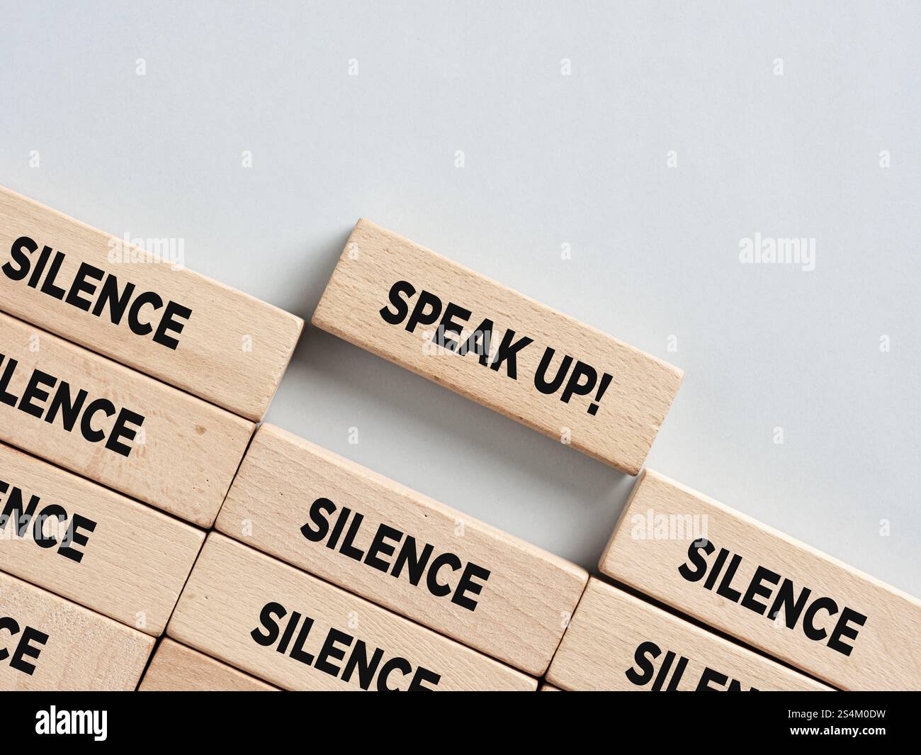 Les blocs de bois orthographiant le silence sont interrompus par un bloc exhortant à parler, symbolisant le pouvoir d'exprimer des opinions contre l'oppression Banque D'Images