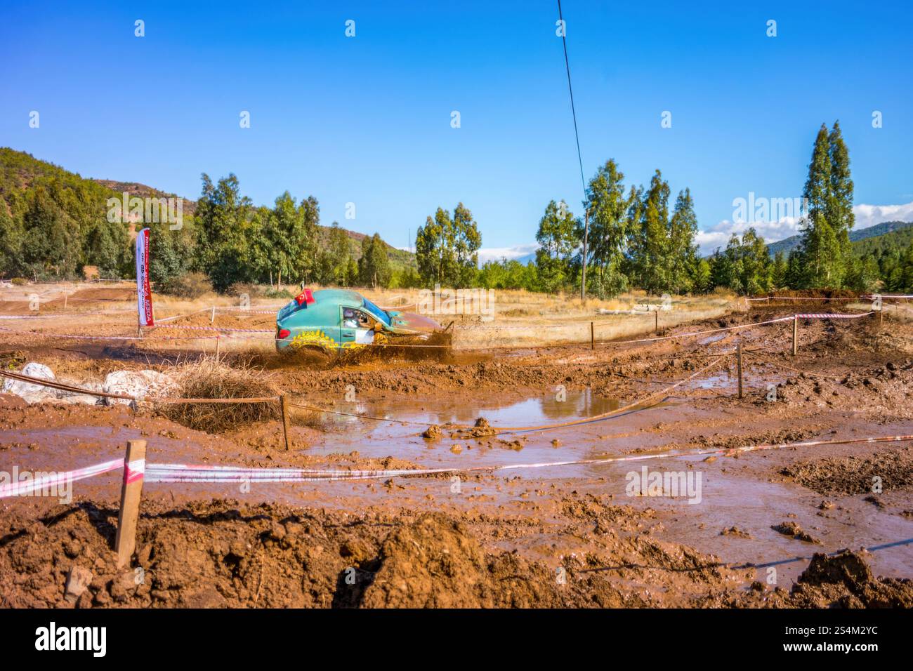 courses tout-terrain. On voit une voiture éclabousser à travers une flaque boueuse, dégageant la saleté Banque D'Images