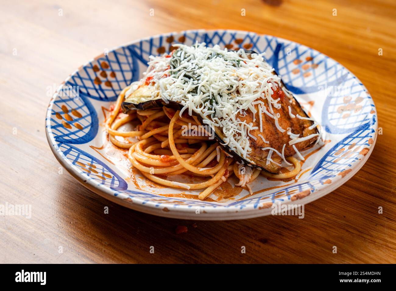 Authentique plat sicilien de Pasta alla Norma avec sauce tomate, aubergines, basilic frais et fromage râpé sur une plaque en céramique peinte à la main, soulignant R Banque D'Images