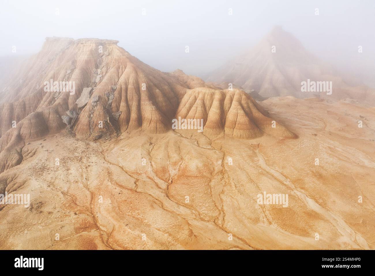 Vue aérienne des formations désertiques accidentées enveloppées de motifs d'érosion de brume sont visibles sur la surface sablonneuse, créant une atmosphère mystérieuse et surréaliste Banque D'Images