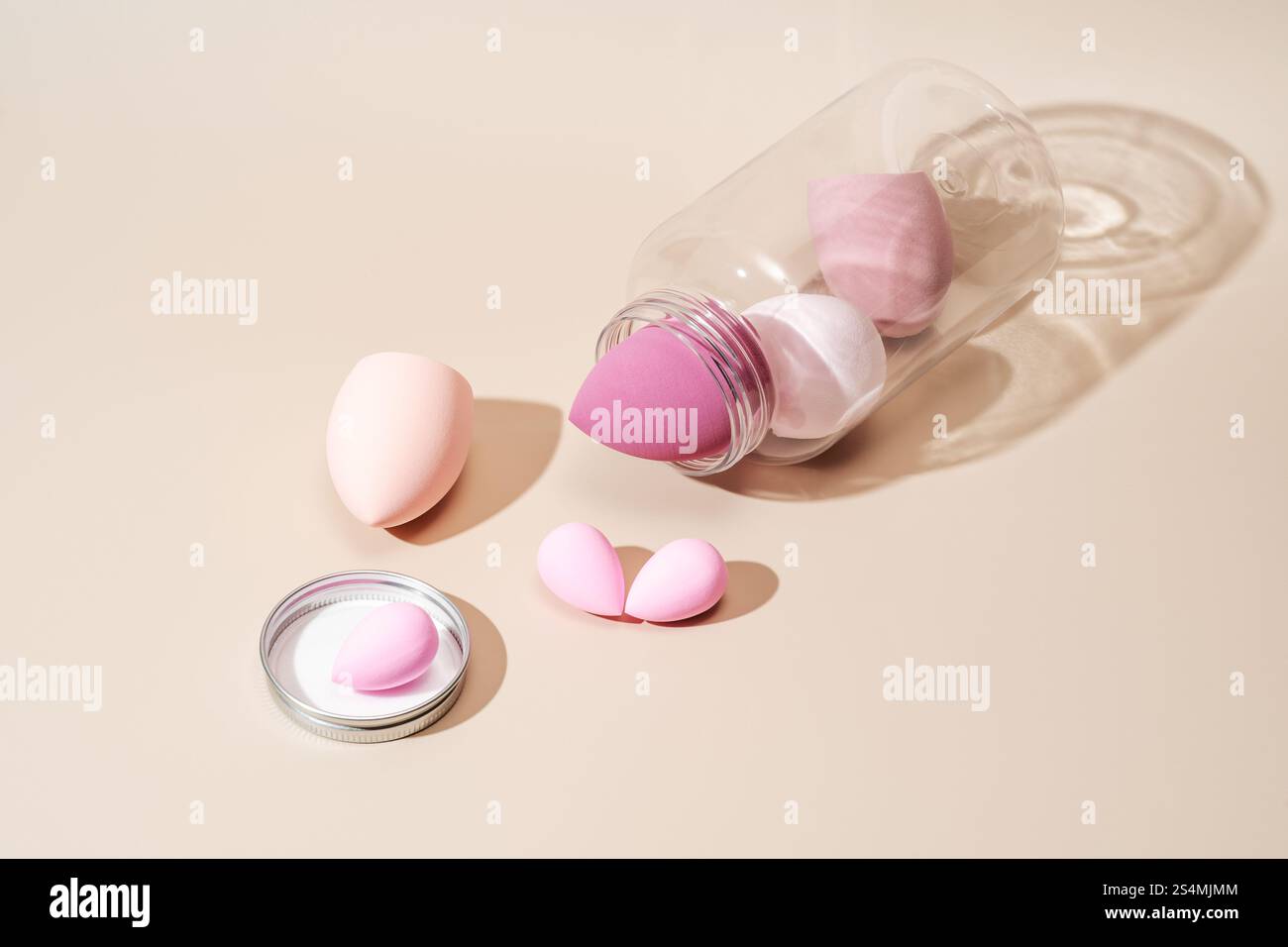 Une variété d'éponges cosmétiques de couleur pastel sont artistiquement disposées sur un fond neutre. Elles offrent une approche moderne de l'application du maquillage, enh Banque D'Images