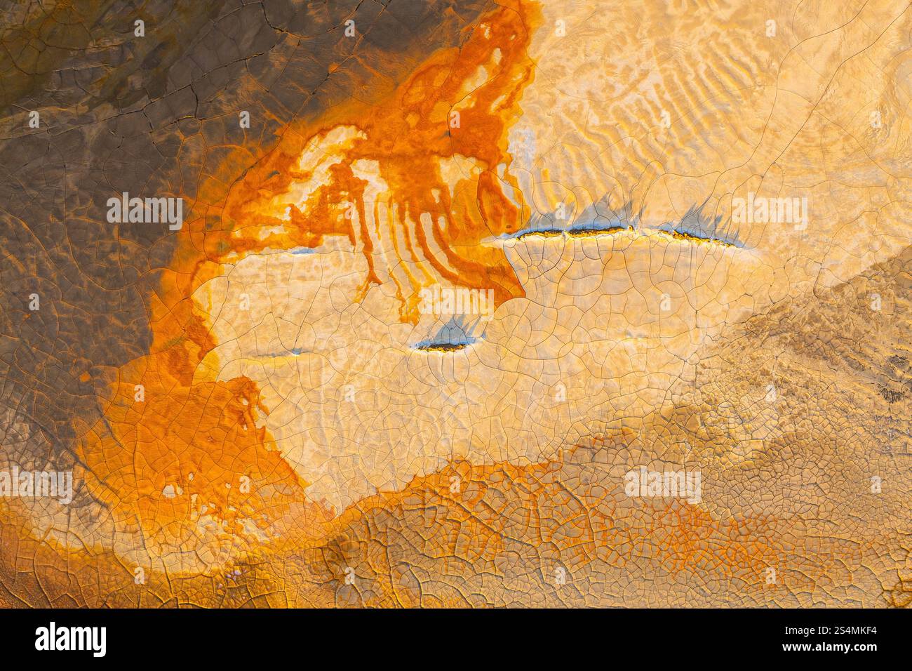 Vue aérienne de motifs de boue multicolores vibrants mettant en valeur des teintes orange, marron et terreuses. Les textures craquelées créent un paysage abstrait Banque D'Images
