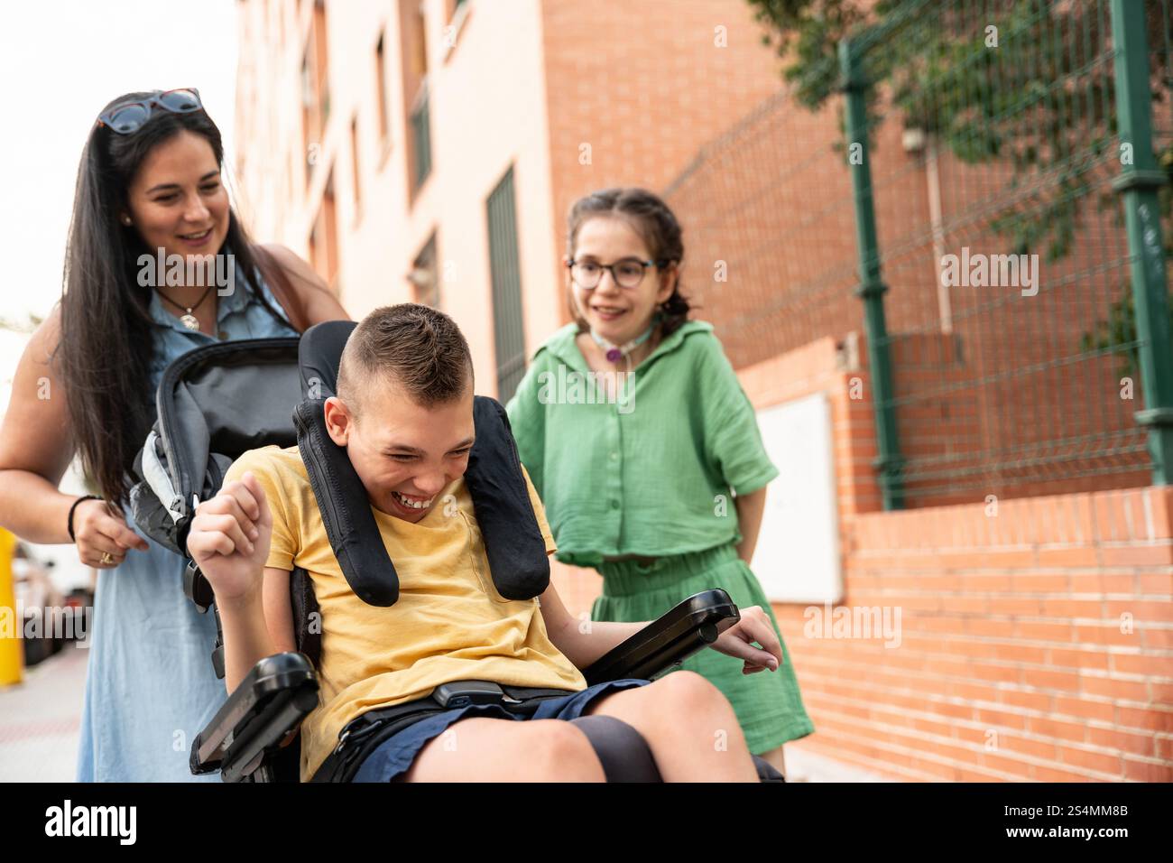 La famille aime le temps en plein air, avec une fille avec trachéotomie et un garçon avec paralysie cérébrale. Souriant, riant et embrassant la diversité, ils partagent M. Banque D'Images La famille aime le temps en plein air, avec une fille avec trachéotomie et un garçon avec paralysie cérébrale. Souriant, riant et embrassant la diversité, ils partagent M. Banque D'Images