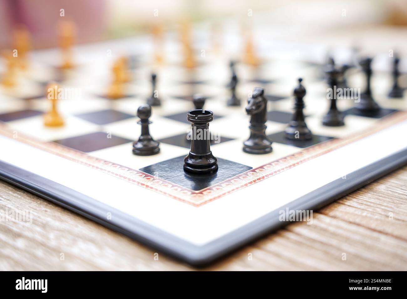 Gros plan d'un échiquier sur une table en bois à l'extérieur pièces noires et blanches arrangées pour un jeu en cours, capturant le jeu stratégique et détendu a Banque D'Images