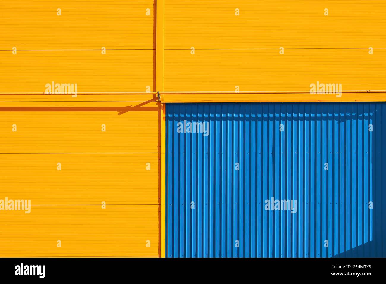 Détail d'un bâtiment d'entrepôt industriel avec des murs jaunes et une porte bleue comme fond minimaliste abstrait Banque D'Images