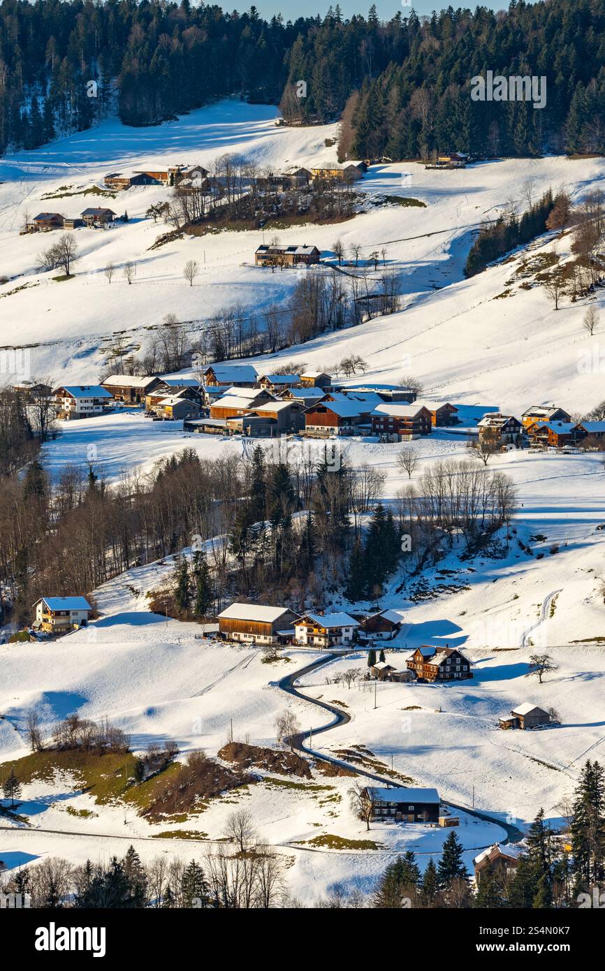 Village alpin, Autriche en hiver, enneigé éparpillé dans la vallée avec des montagnes, dans la vallée est une collection de fermes entre les forêts Banque D'Images
