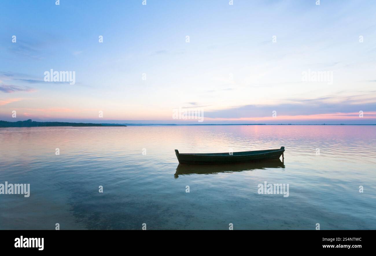 Coucher du soleil et l'ancien bateau de pêche en bois sur le lac d'été (Banque Svityaz, Ukraine) Banque D'Images