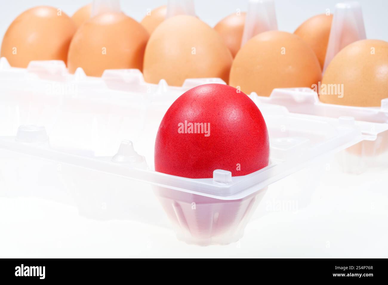 Un oeuf de poule rouge contre plusieurs oeufs brun Banque D'Images