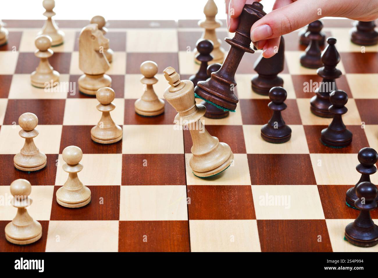 La main avec roi noir pousse roi blanc sur échiquier dans la partie d'échecs Banque D'Images