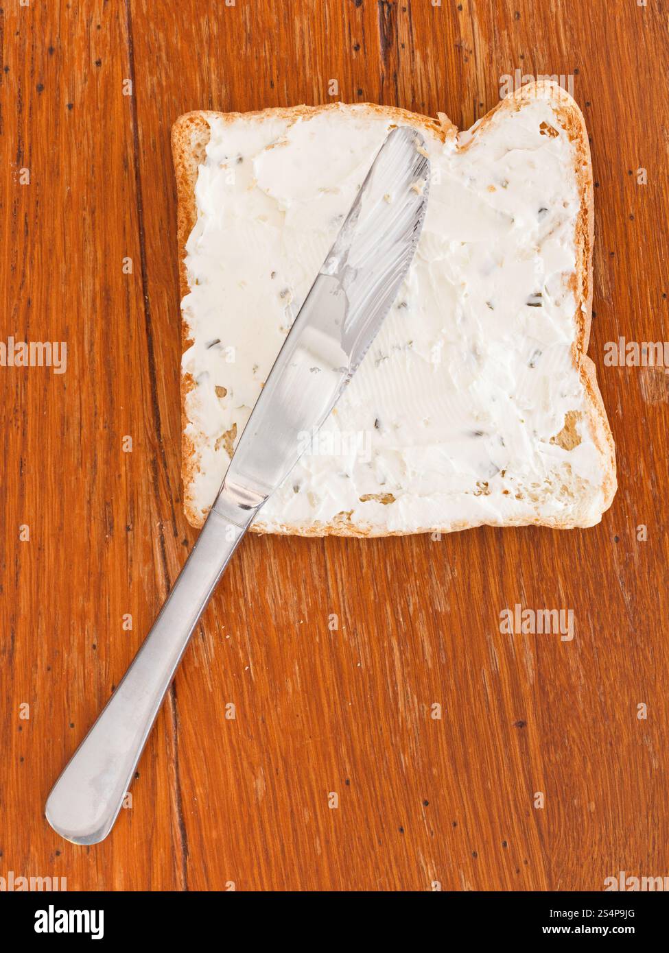 Sandwich de pain grillé et fromage aux herbes, couteau de table sur une table en bois Banque D'Images