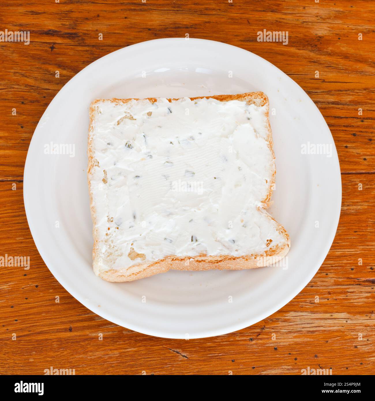 Sandwich de pain grillé et fromage aux herbes sur plaque blanche sur table en bois Banque D'Images